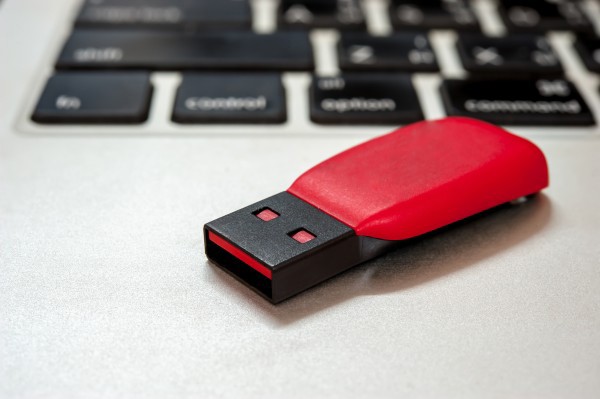 Red and black USB stick on top of a keyboard.