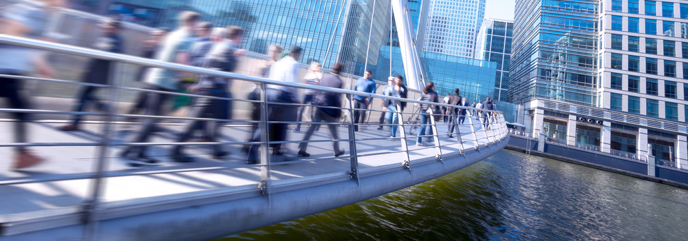 Blurred image of people walking over a bridge.